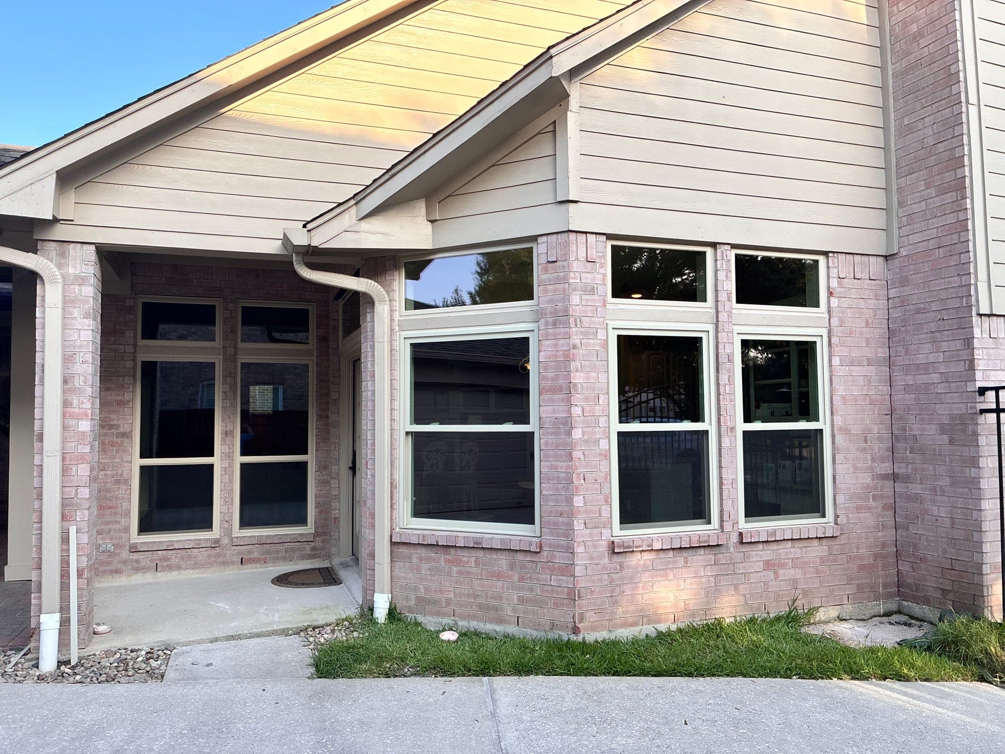 Almond-framed single-hung windows with transoms in a projecting bay corner on blush brick