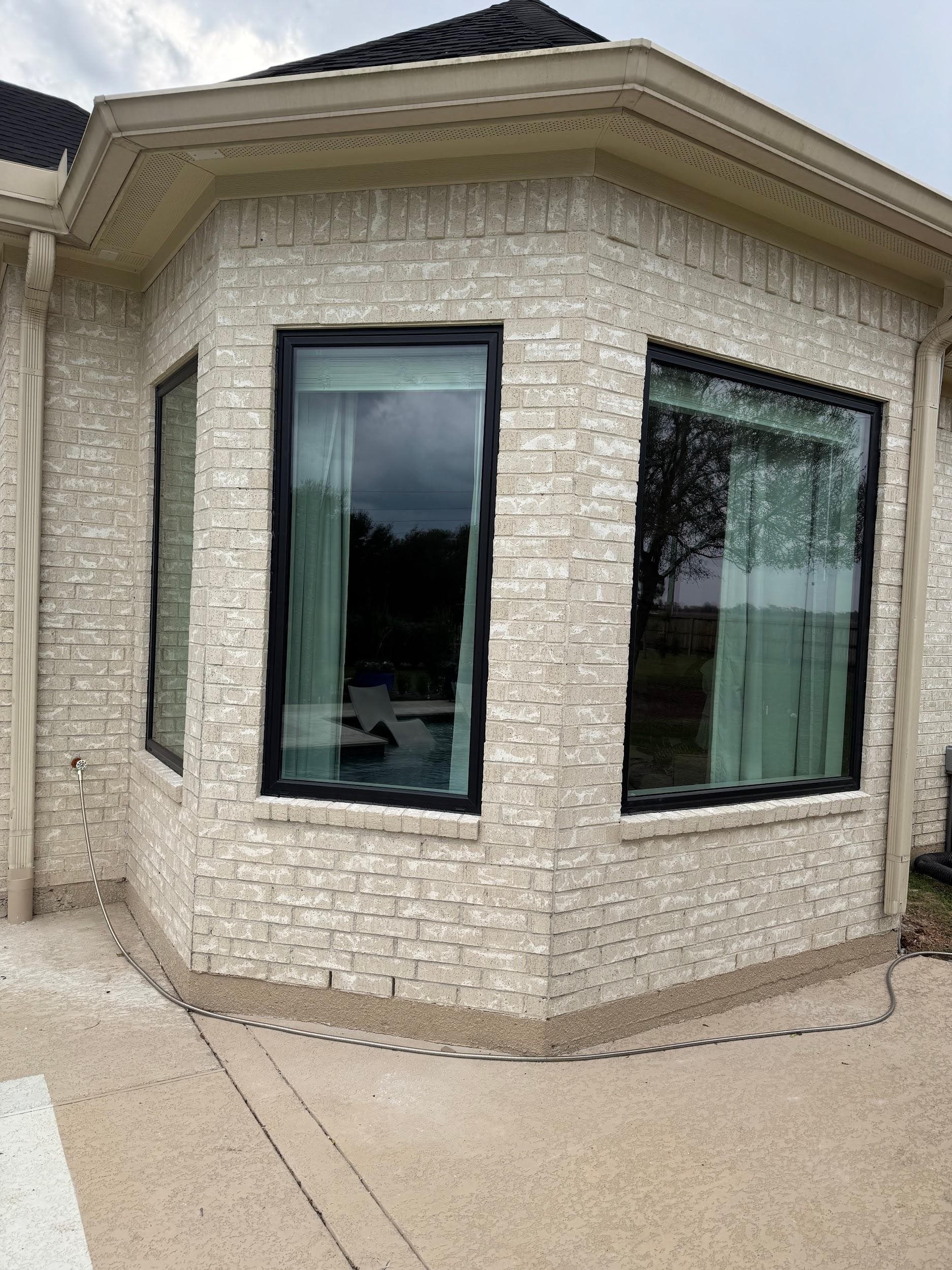 Black-framed bay window projecting from a cream limestone-brick wall