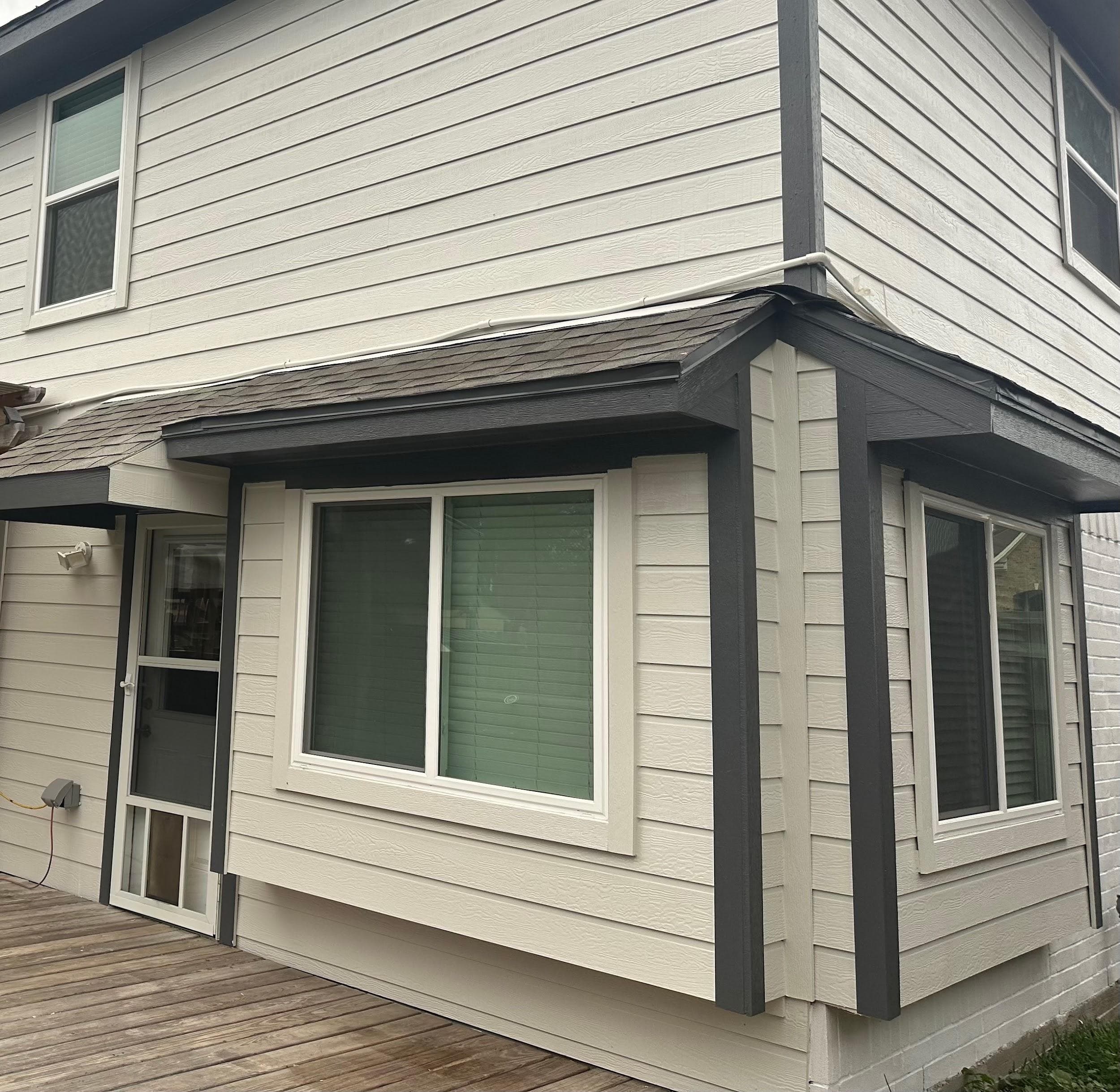 White-framed windows in a projecting bay bump-out on gray lap siding