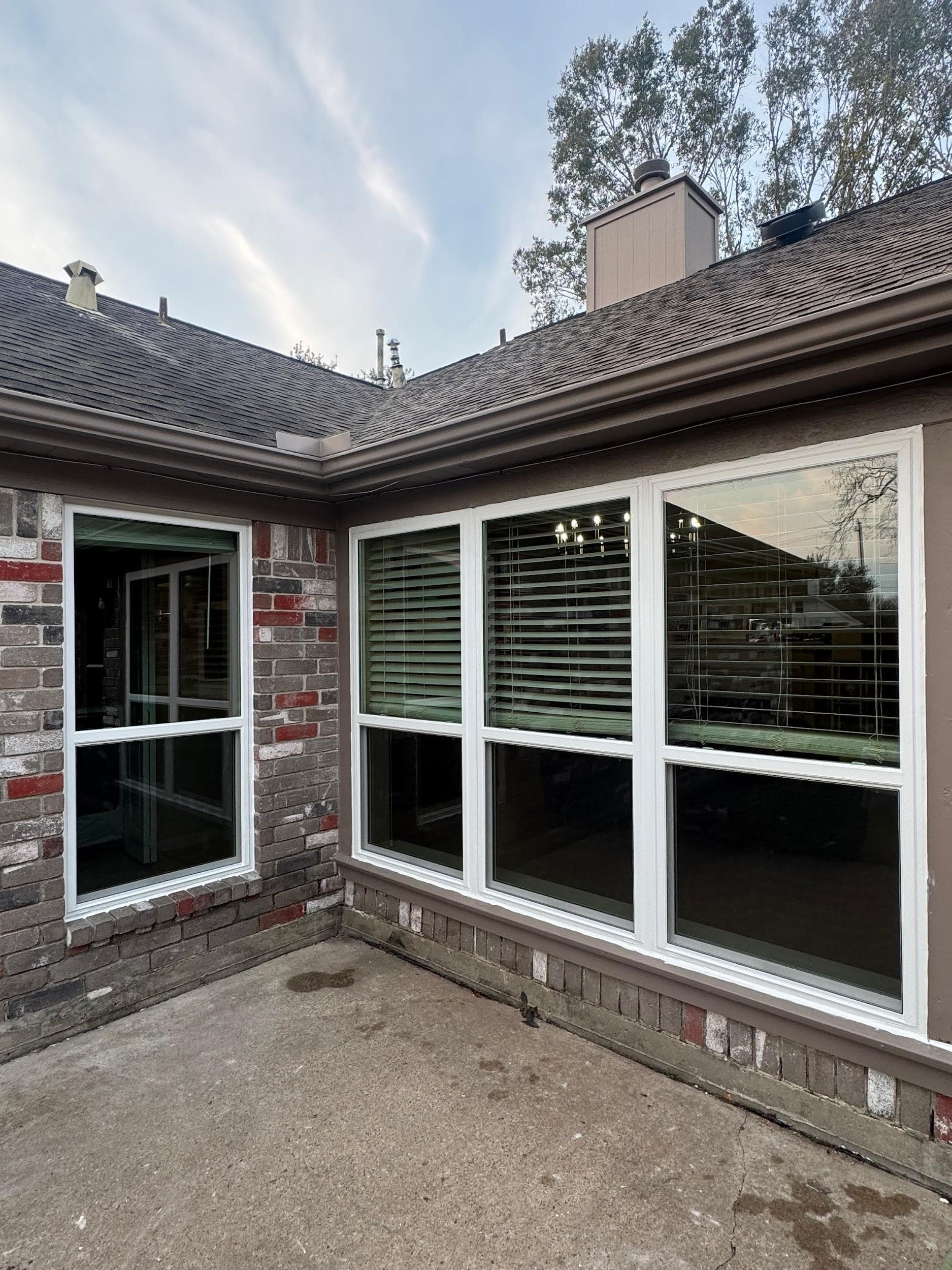 Large white-framed picture window with a transom beside a narrow slider on brick