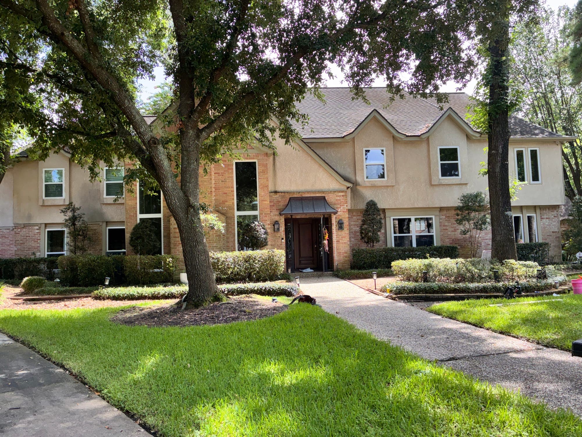 Stucco-and-brick estate with tall white picture windows and single-hungs