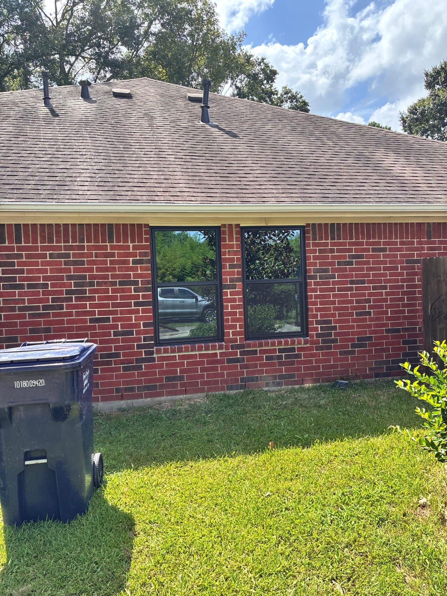 Two black-framed single-hung windows on a red-brick ranch elevation