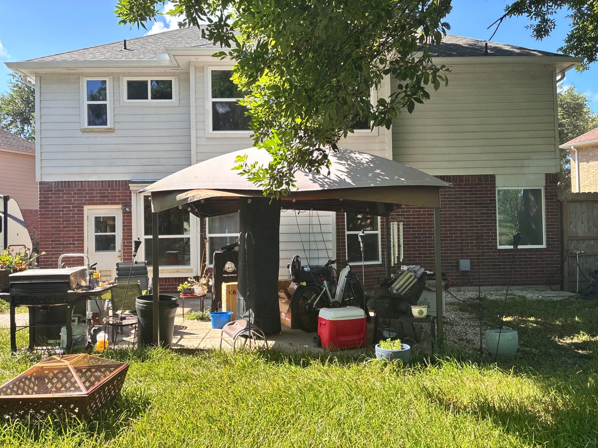 Backyard elevation of a two-story brick-and-siding home with white single-hung windows