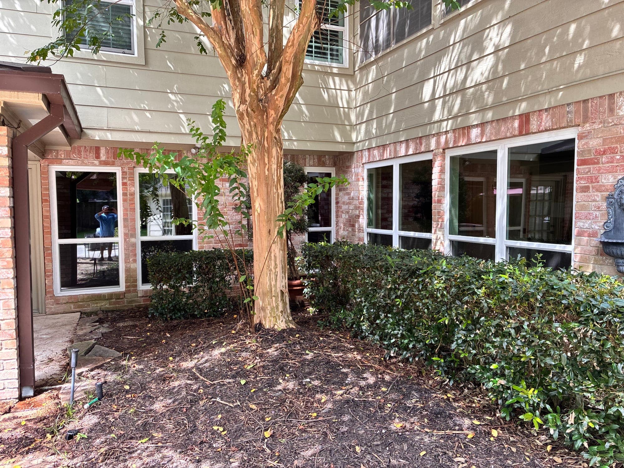 A row of white single-hung windows wrapping a brick-and-siding courtyard corner