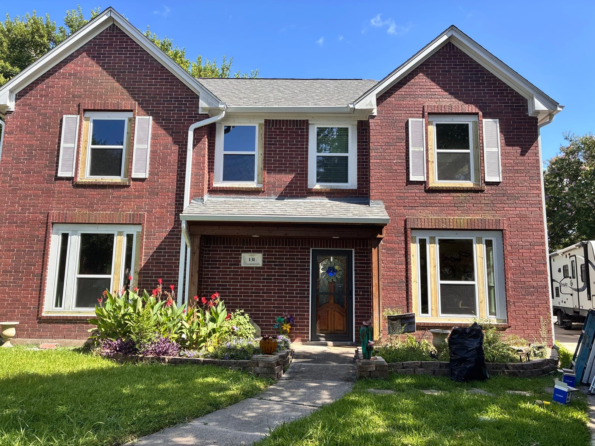 Two-story red-brick home with new white single-hung windows and white shutters