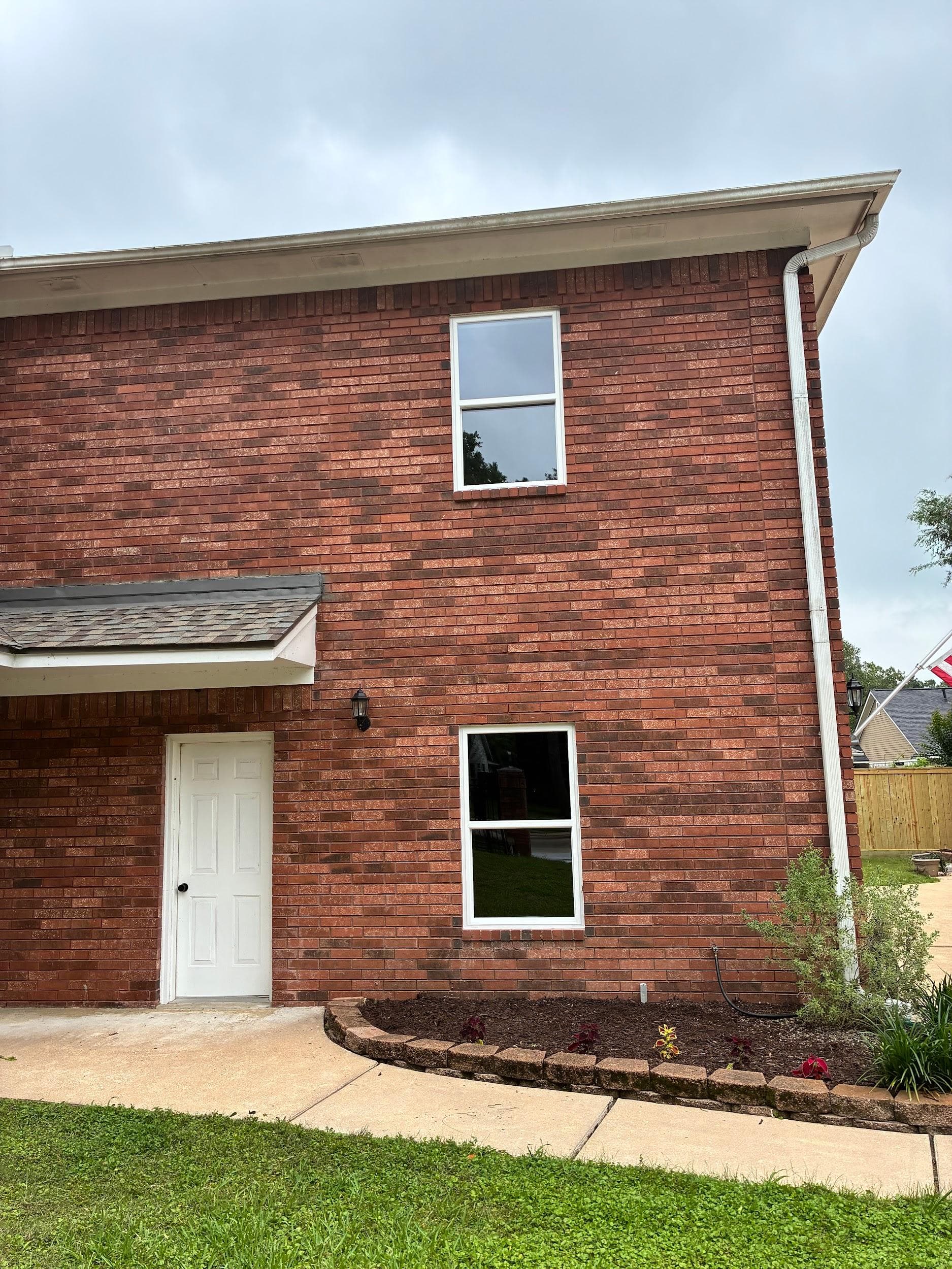 Two white single-hung windows stacked on a two-story red-brick elevation