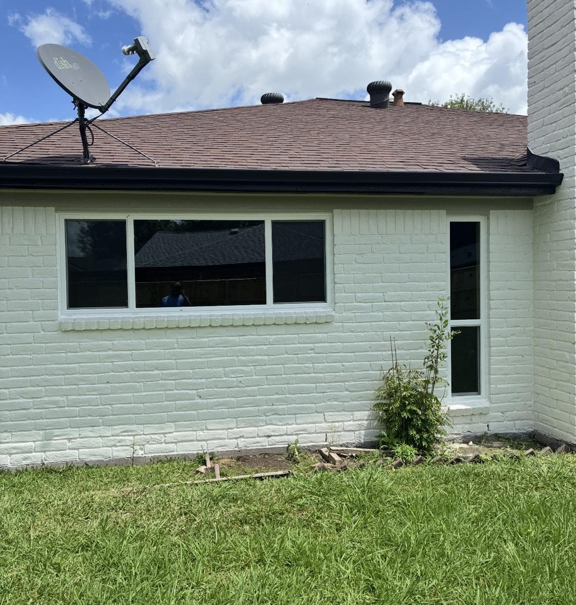 Wide white-framed slider on a sage-green painted brick wall