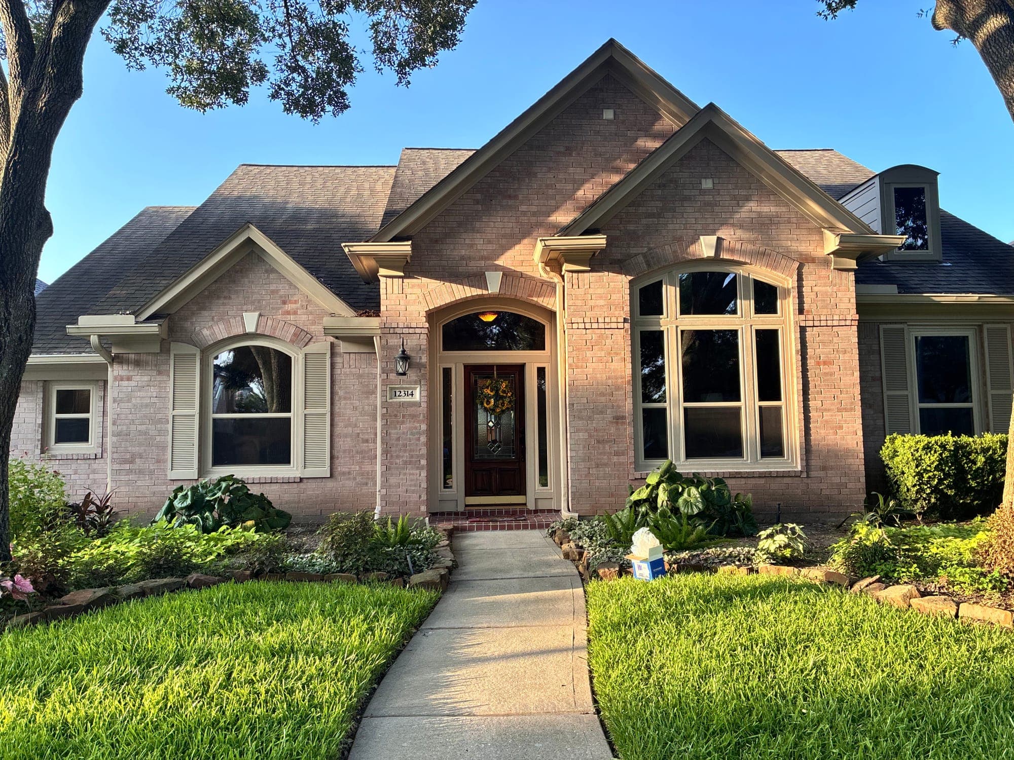 Blush-brick home with almond-framed arch-top windows and shutters