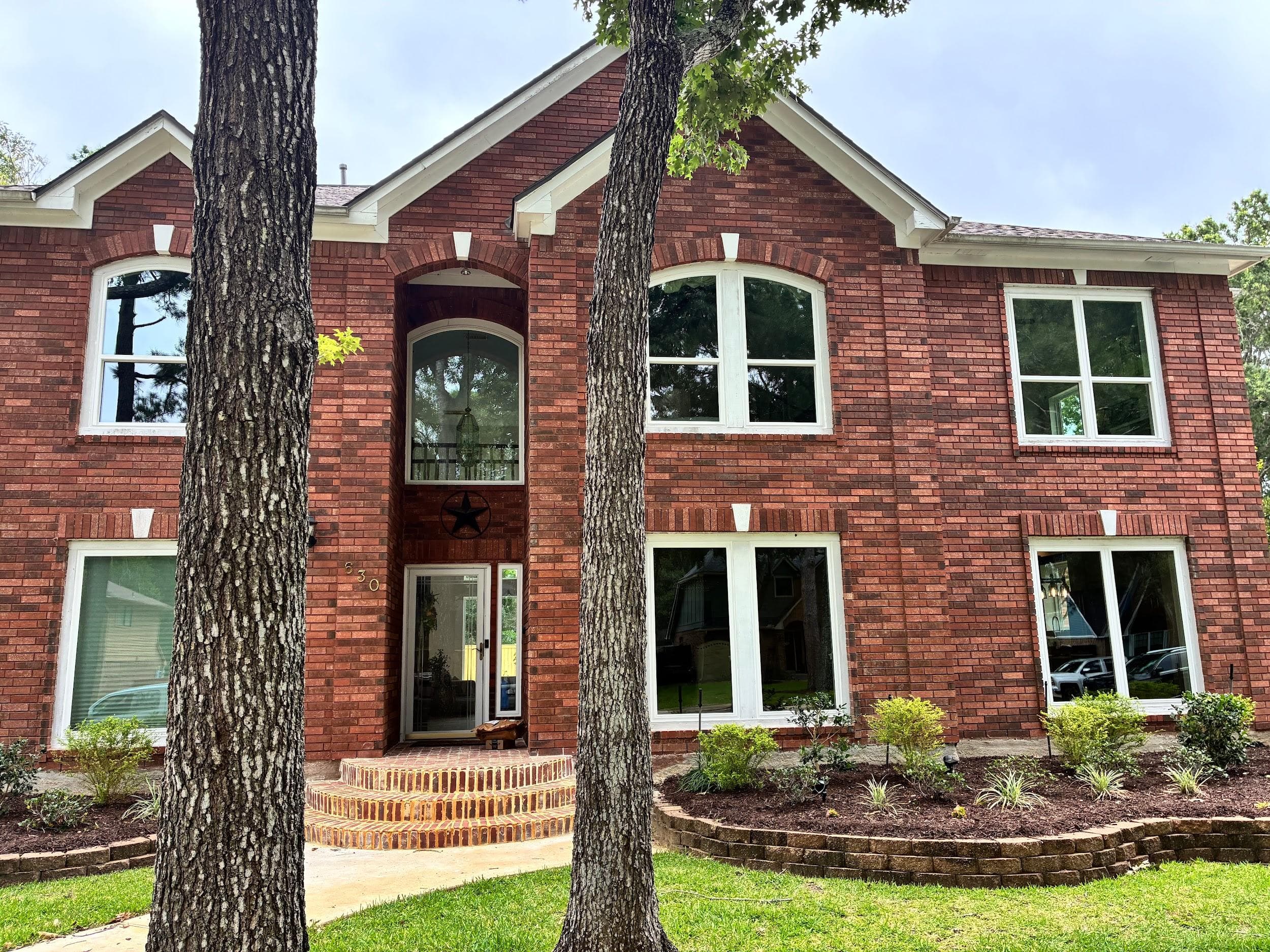 Two-story red-brick home with white windows and arched transoms over the entry
