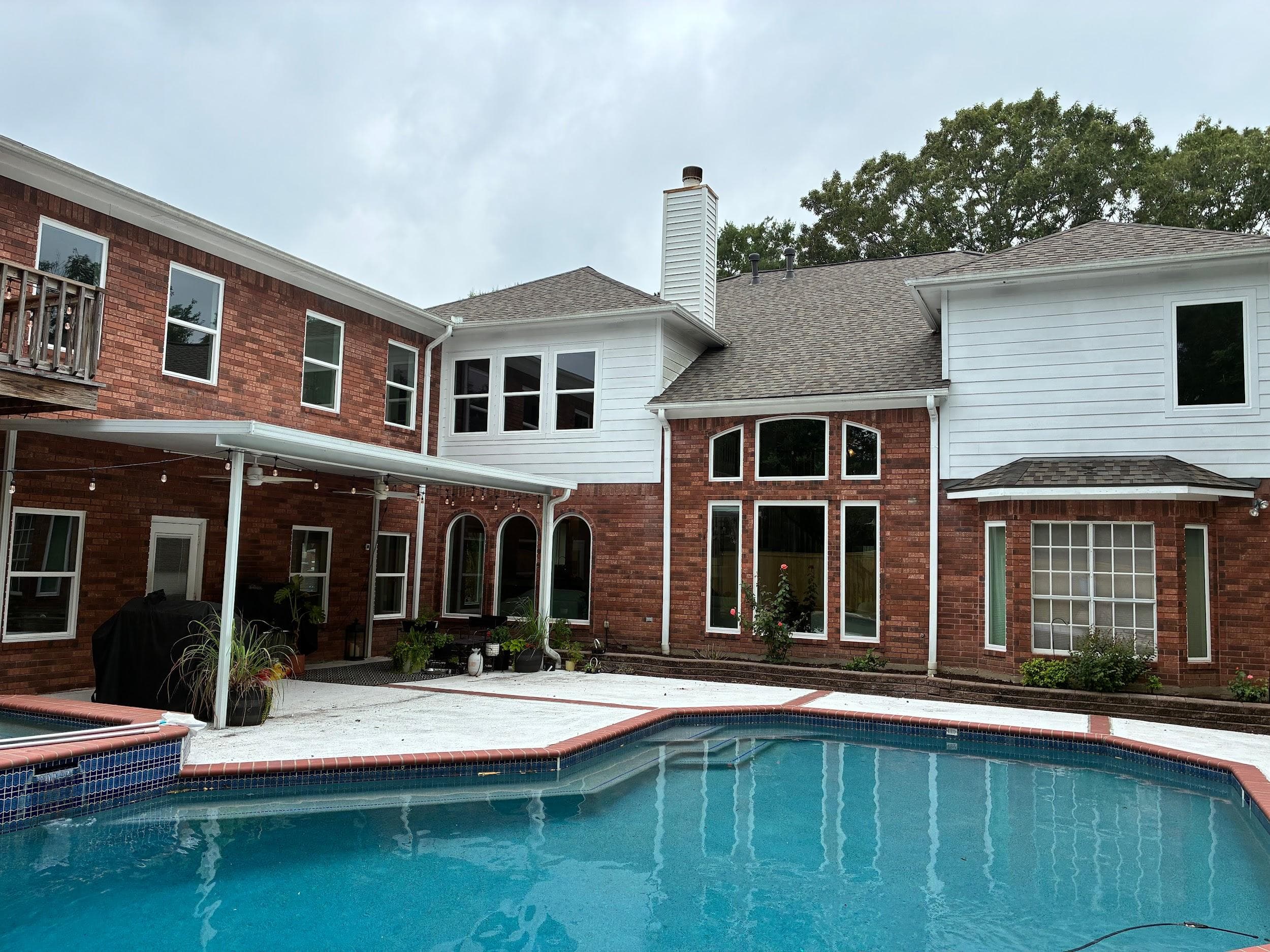Two-story home beside a pool with white-framed picture and arch-top windows
