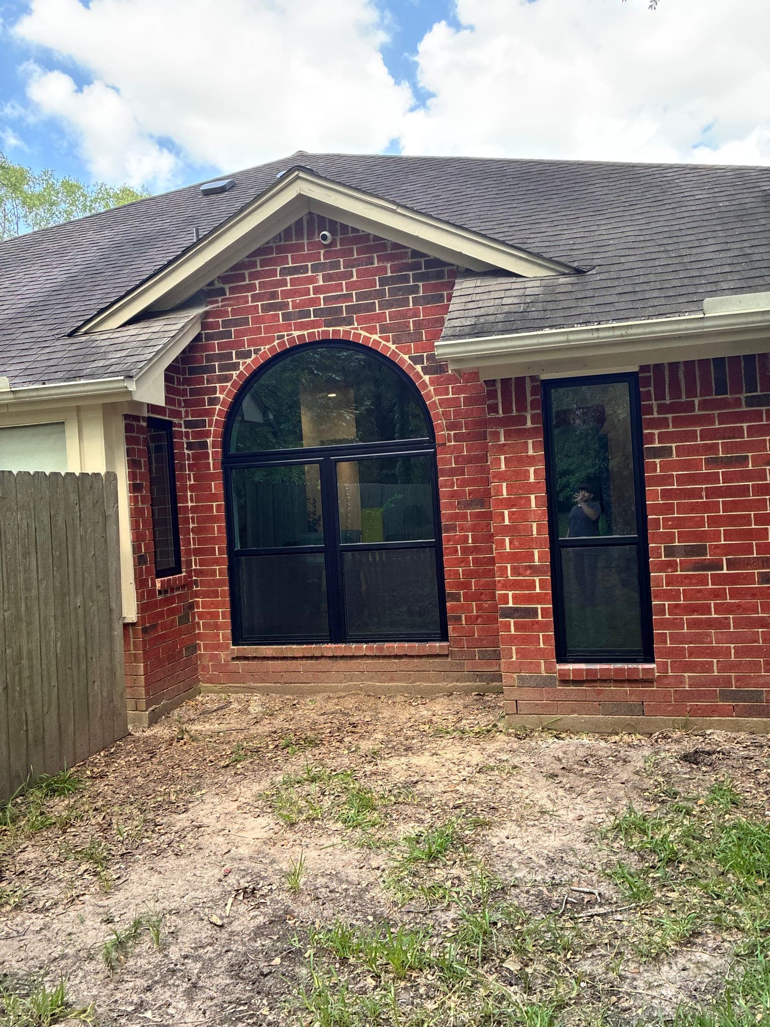 Black-framed arch-top window combination centered in a red-brick gable