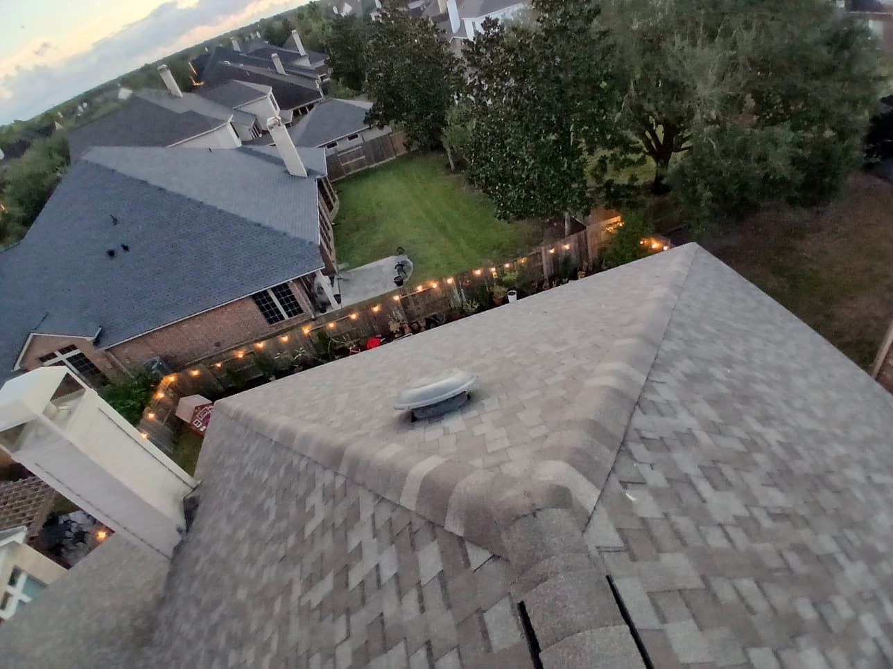 Completed hip and ridge with attic vent dome at dusk on a Houston home