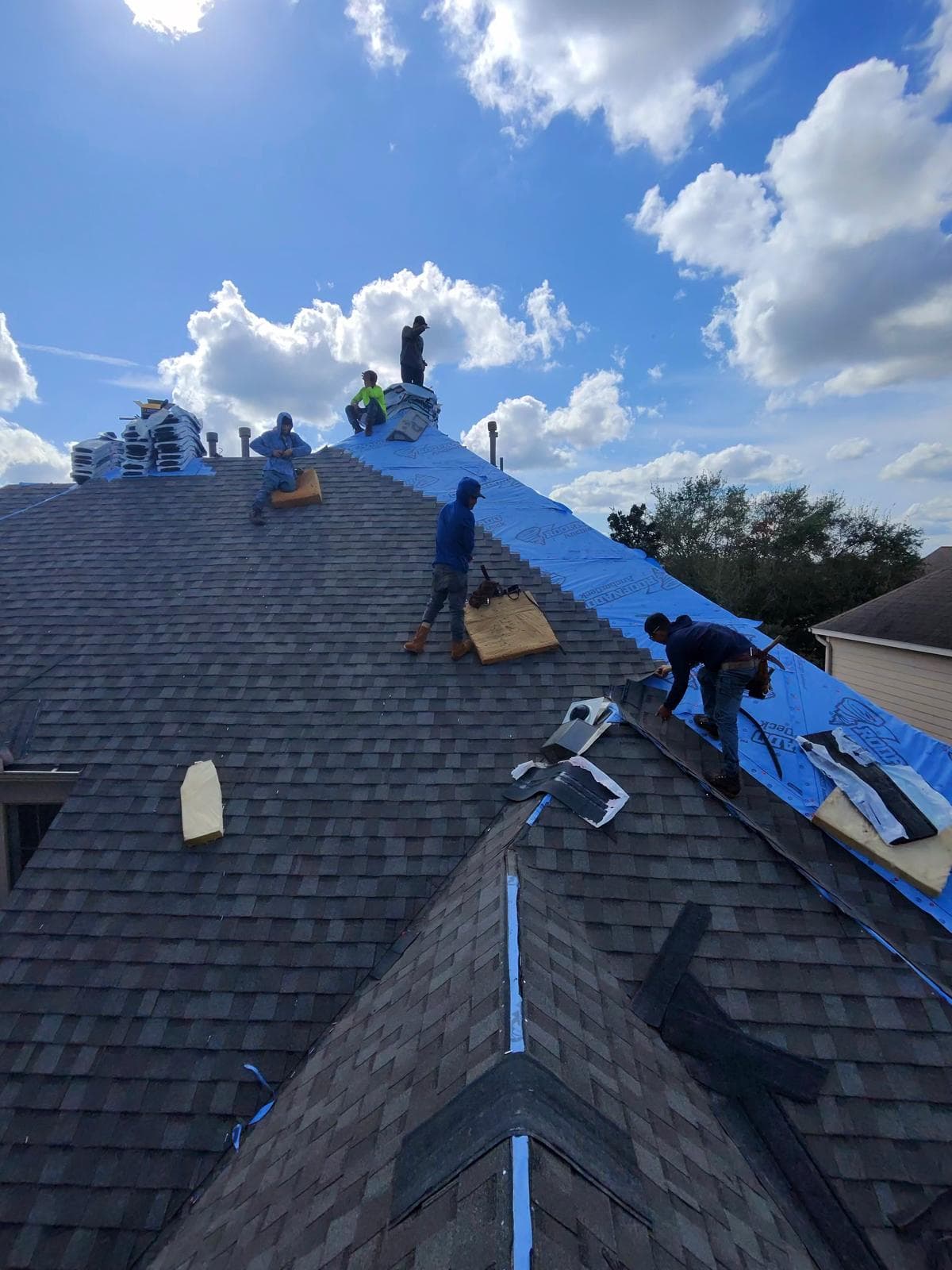 Five-man Bluebonnet crew shingling up a steep slope over synthetic underlayment